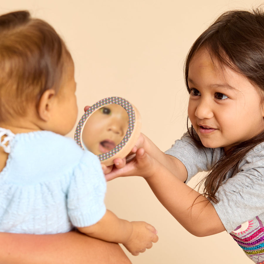 Children looking into round discovery mirrors during shared play