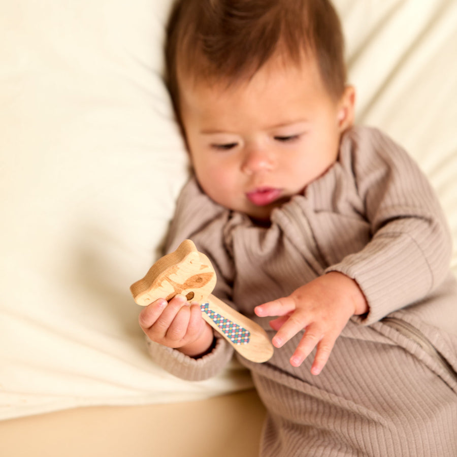 Baby holding a wooden animal-shaped rattle during supervised play