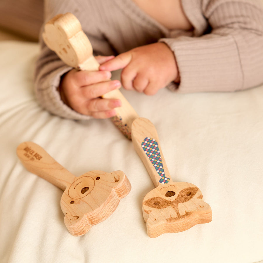 Baby holding a wooden animal-shaped rattle during supervised play