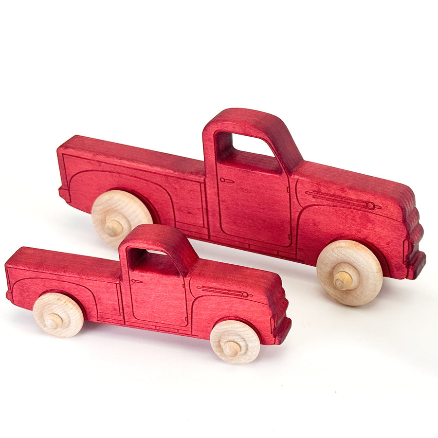 Small and large red wooden toy pickup trucks shown together