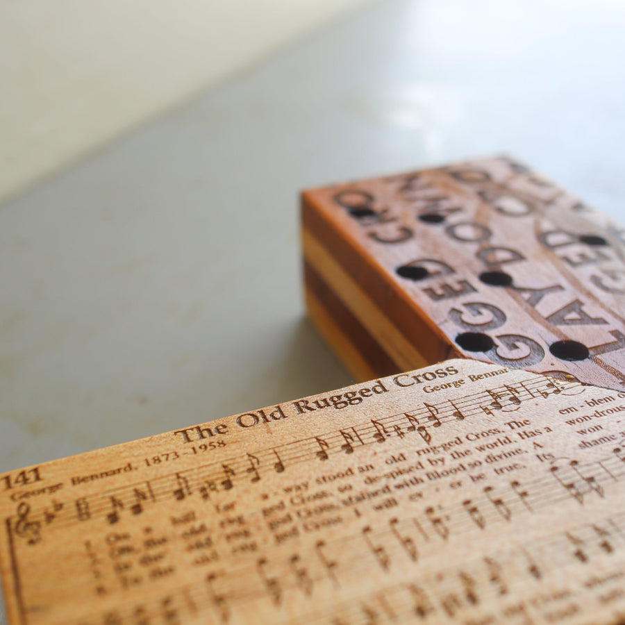 Reclaimed piano wood cross engraved with Old Rugged Cross hymn imagery.