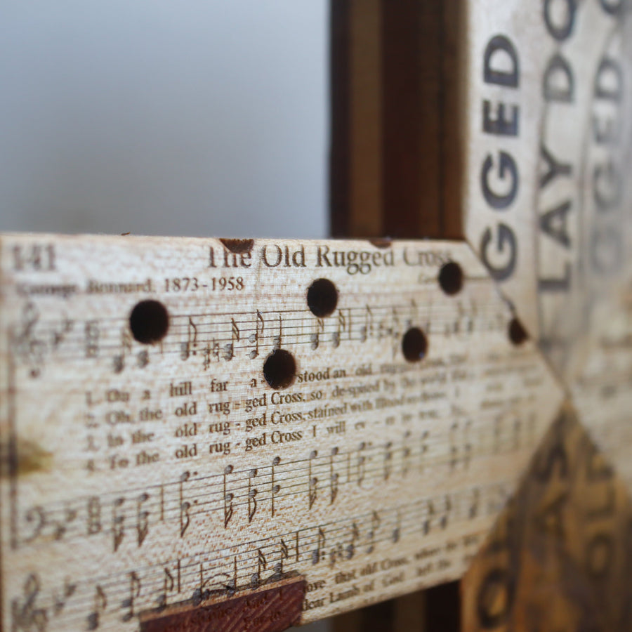 Reclaimed piano wood cross engraved with Old Rugged Cross hymn imagery.