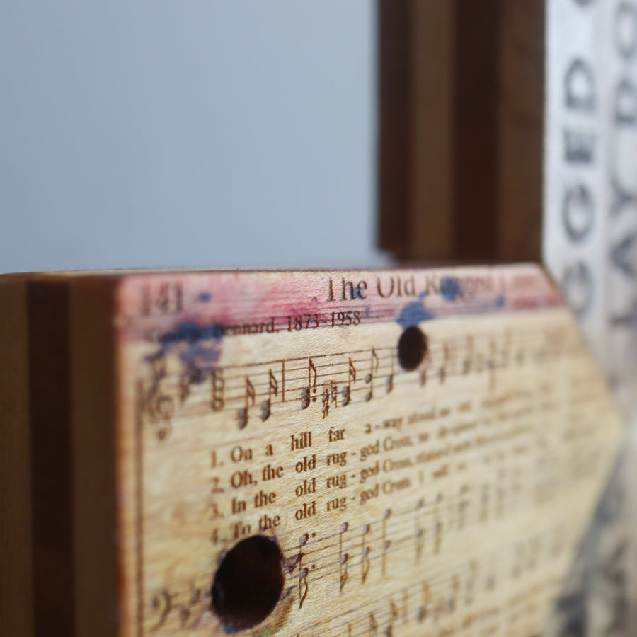 Reclaimed piano wood cross engraved with Old Rugged Cross hymn imagery.