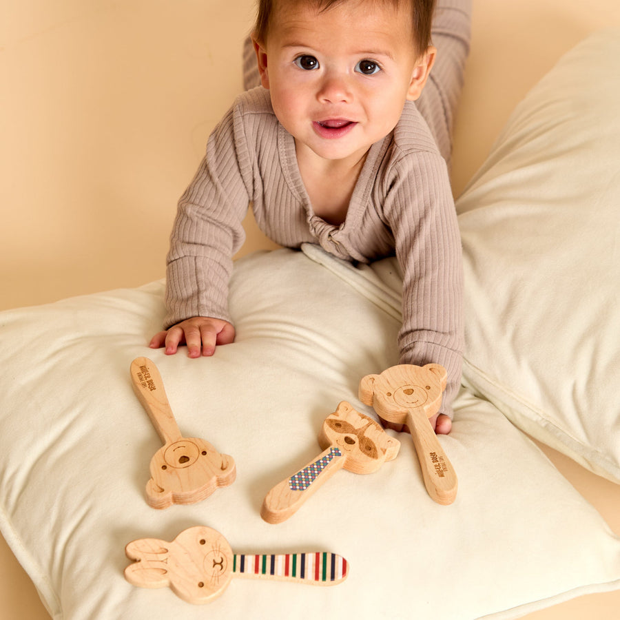 Baby holding a wooden animal-shaped rattle during supervised play