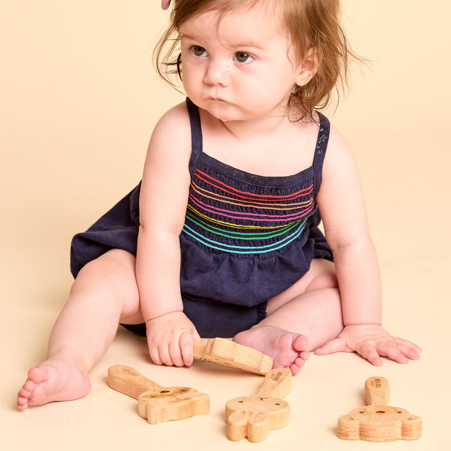 Baby holding a wooden animal-shaped rattle during supervised play