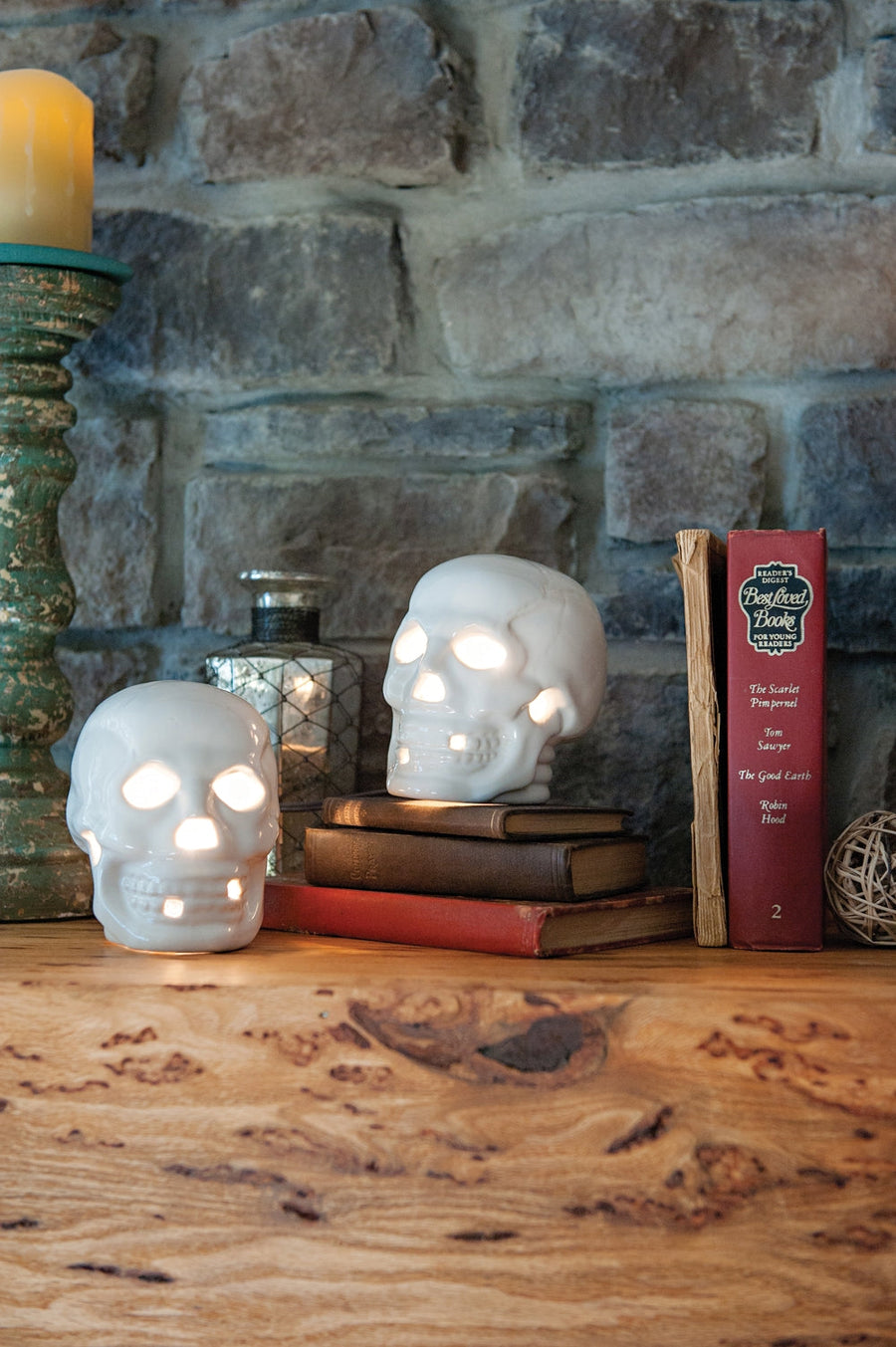 Illuminated stoneware skulls arranged with books; coordinating pieces are separate