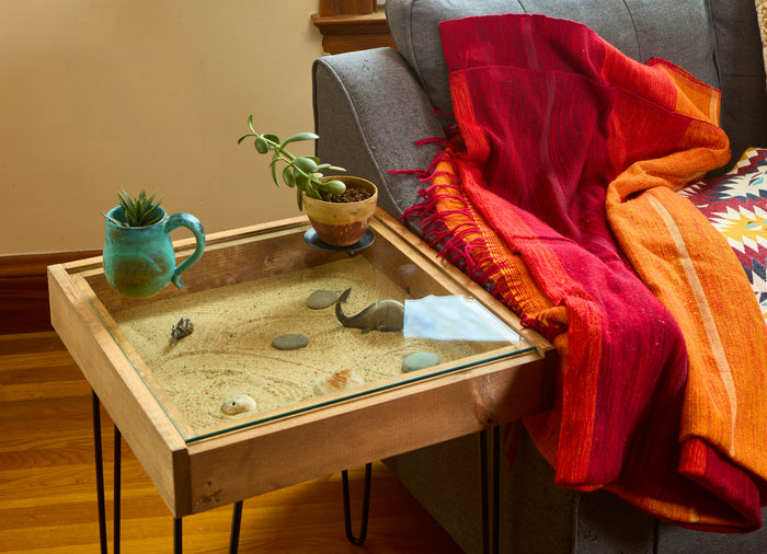 Small glass-top display table holding shells beside a sofa