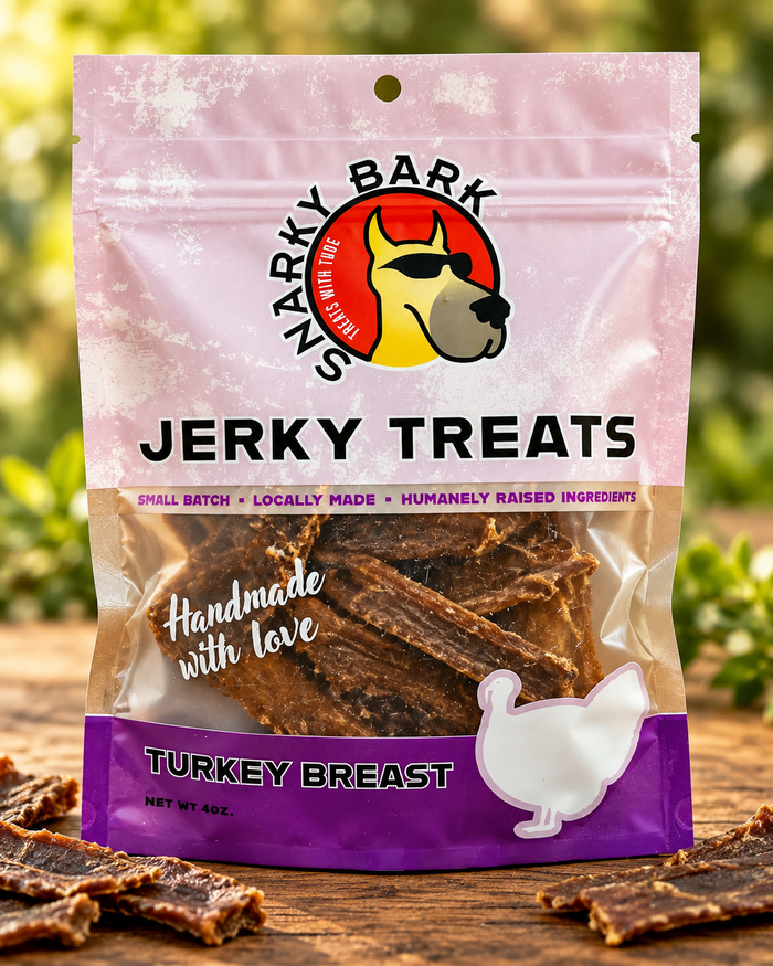 Snarky Bark turkey breast jerky in a pink pouch with strips on a wooden surface