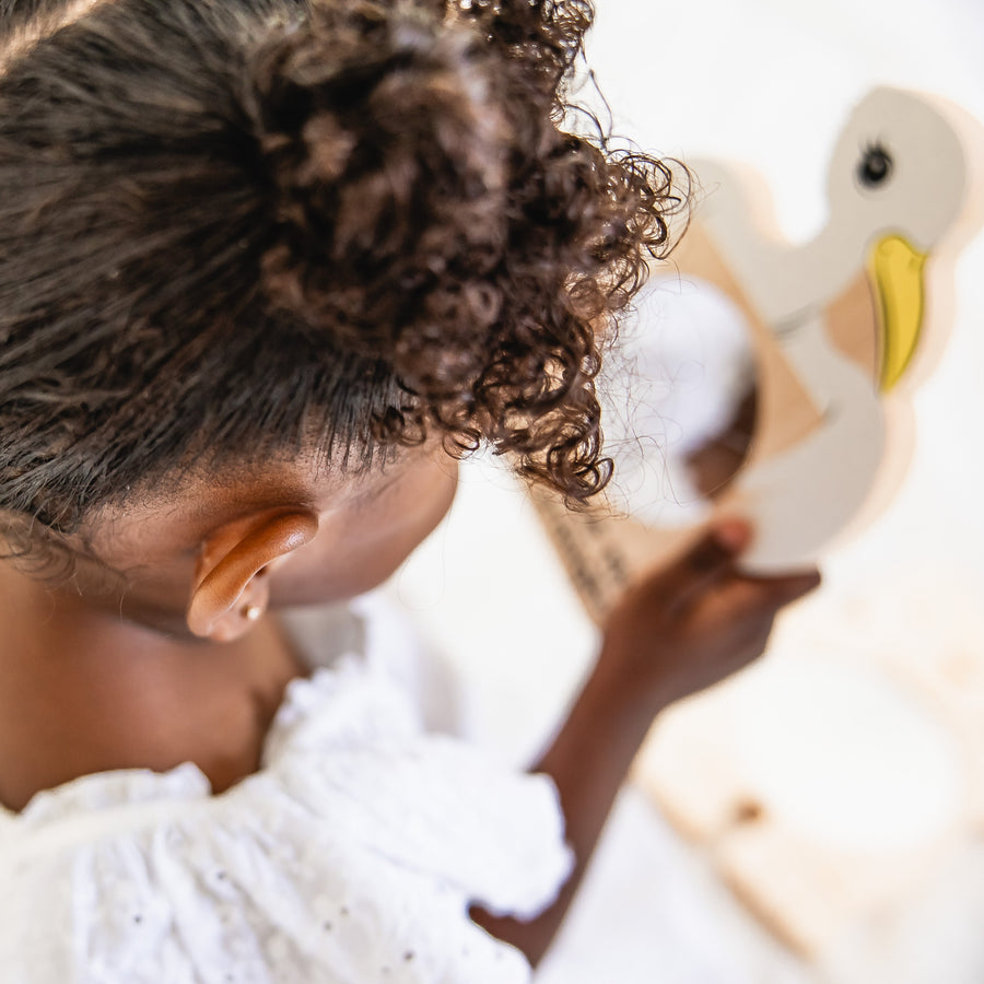 Baby exploring a stork-shaped wooden discovery mirror