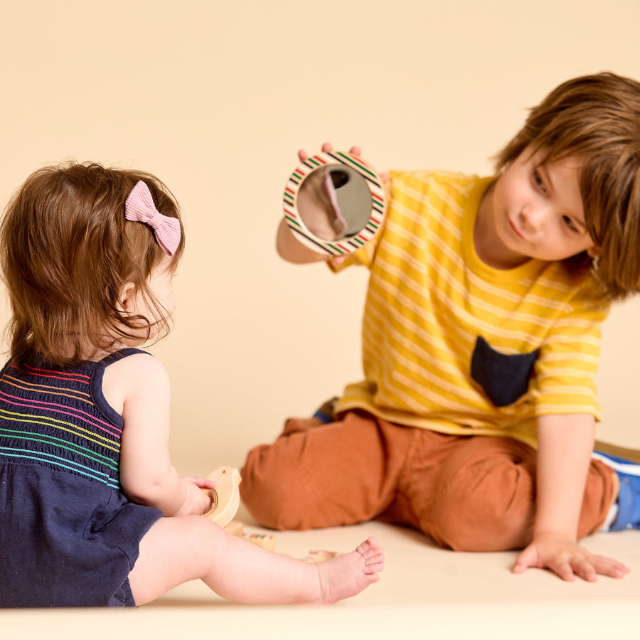 Children looking into round discovery mirrors during shared play