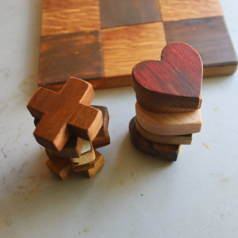 Wooden tic-tac-toe board with heart and X playing pieces.