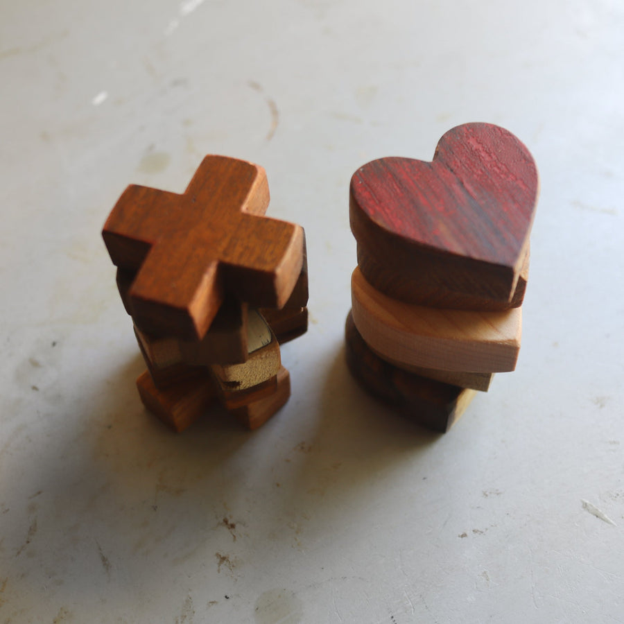 Wooden tic-tac-toe board with heart and X playing pieces.