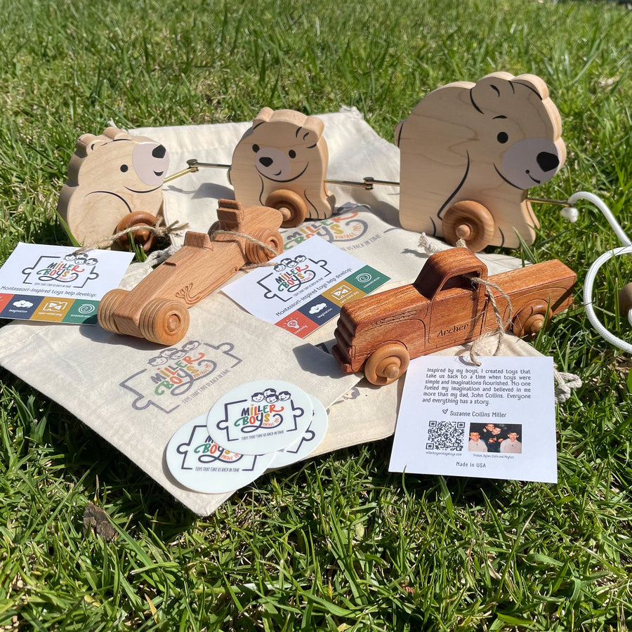 Assorted wooden animal toys and printed storage bags arranged on grass