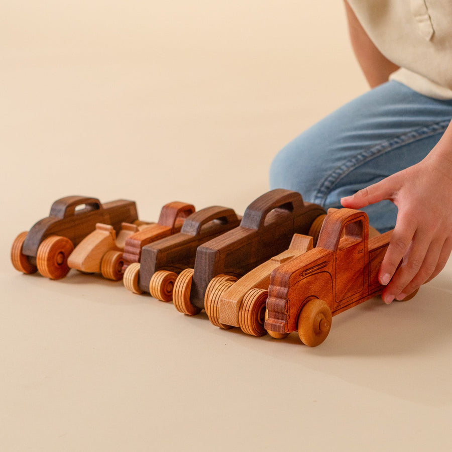 Child arranging an assortment of wooden toy cars