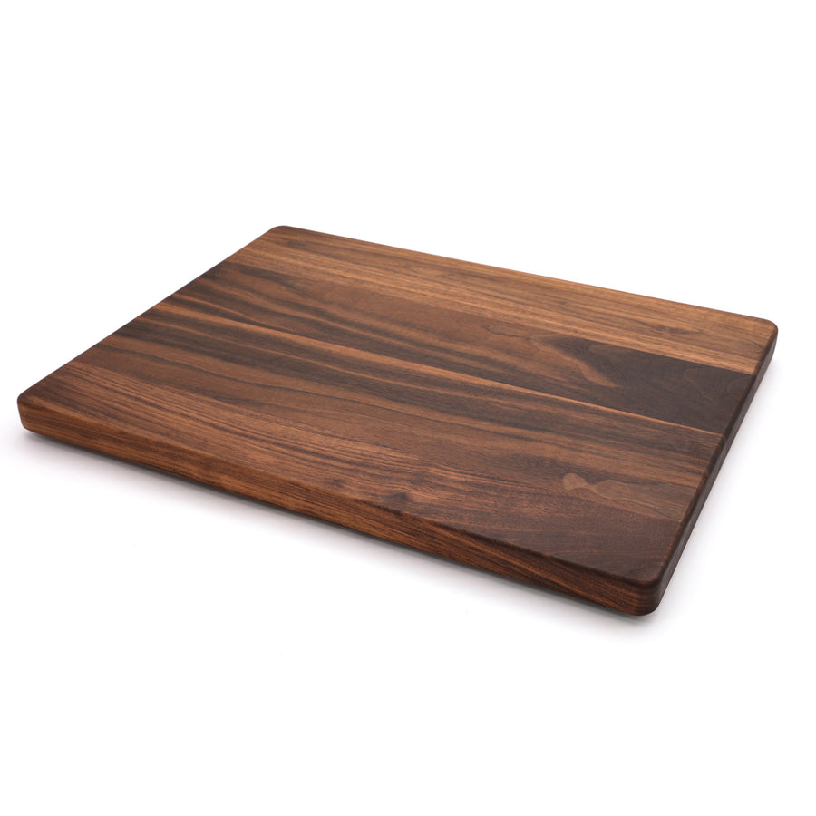 Thick walnut cutting board with a plain surface, angled view