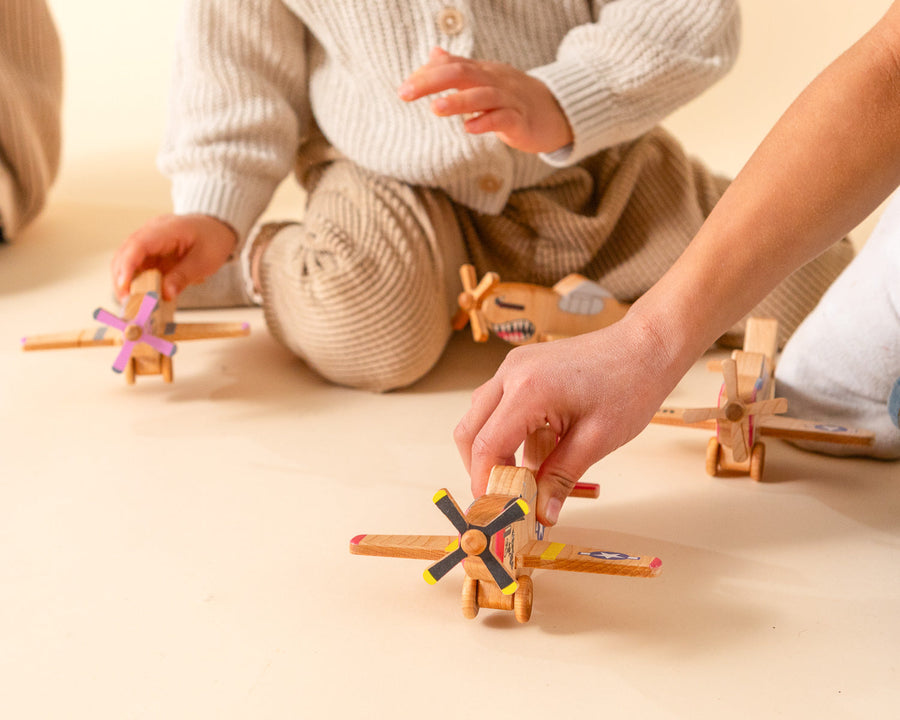 Child’s hands holding and guiding a wooden toy airplane