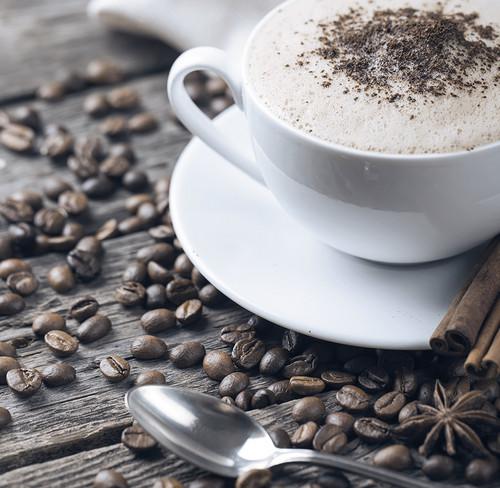 Serving suggestion: creamy coffee in a cup beside coffee beans