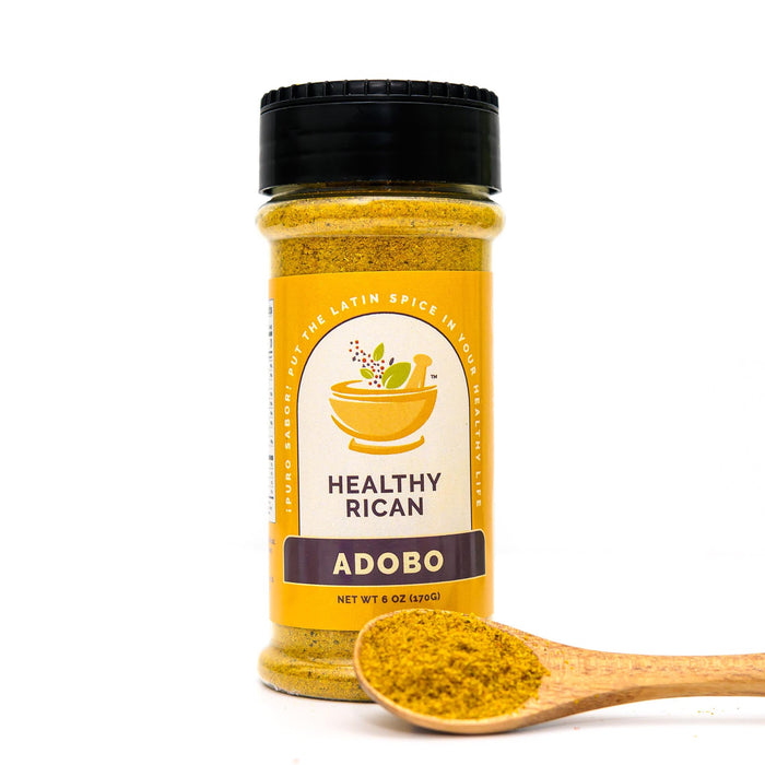 Adobo seasoning jar beside a wooden spoon of golden spice blend