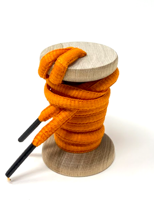 Orange oval athletic shoelaces on a wooden spool