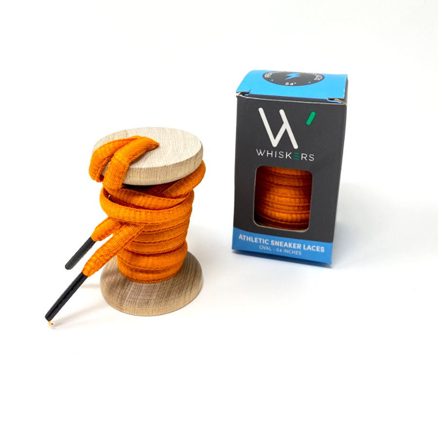 Orange oval athletic shoelaces on a wooden spool beside the retail box