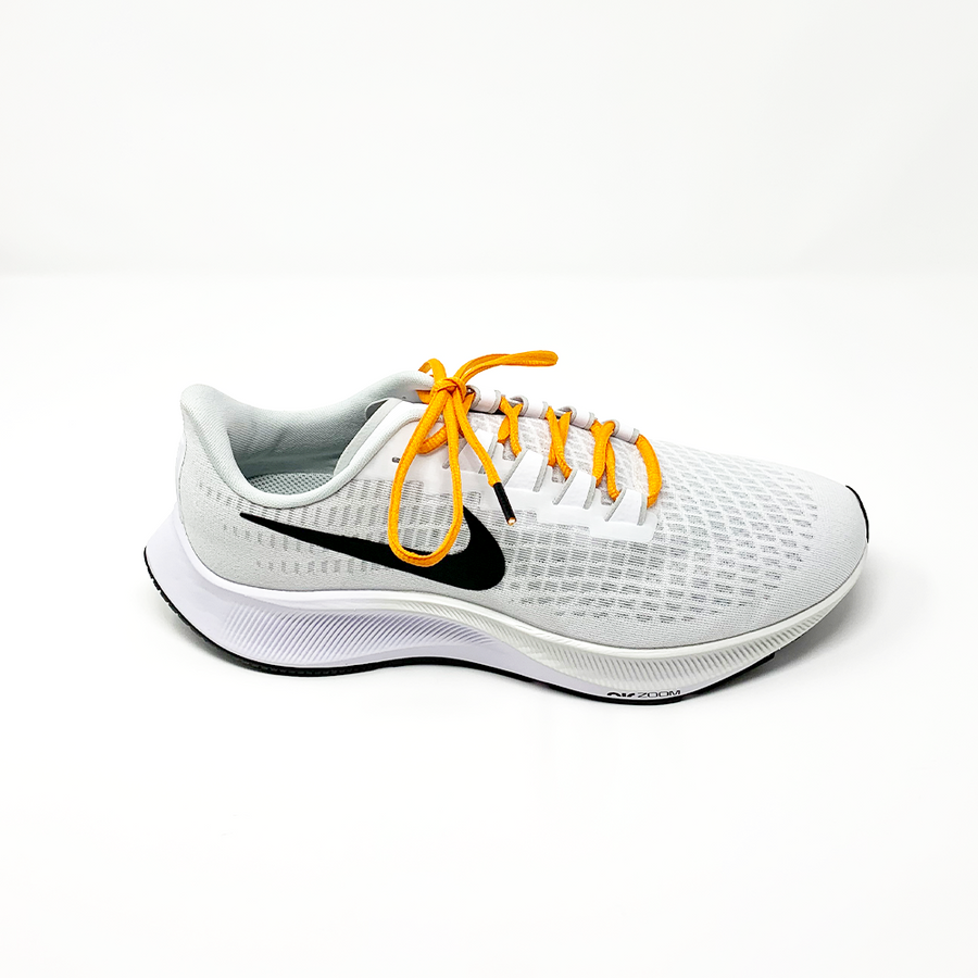 Orange oval athletic shoelaces laced into a light gray running shoe
