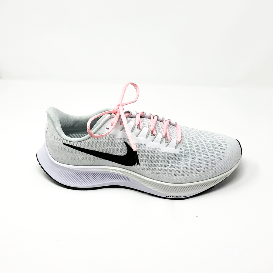 Pink oval athletic shoelaces laced into a light gray running shoe