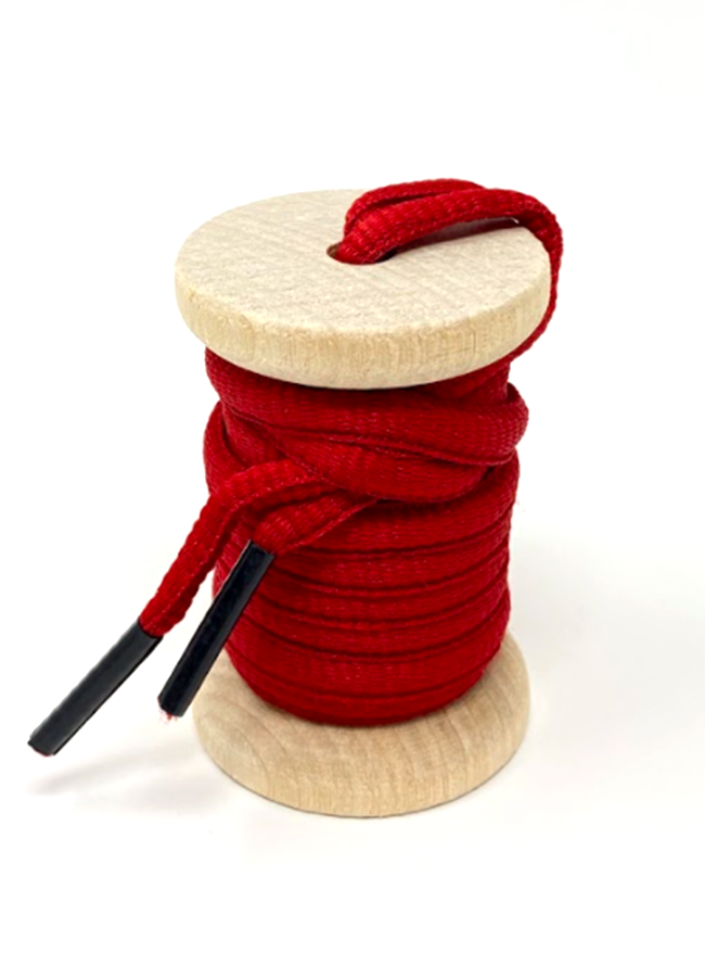 Red oval athletic shoelaces on a wooden spool