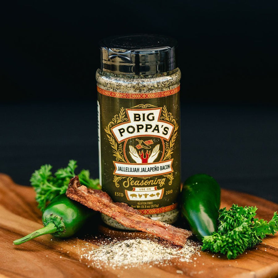 Jallelujah Jalapeño Bacon BBQ Seasoning: Seasoning shaker beside bacon, jalapeños, garlic and parsley