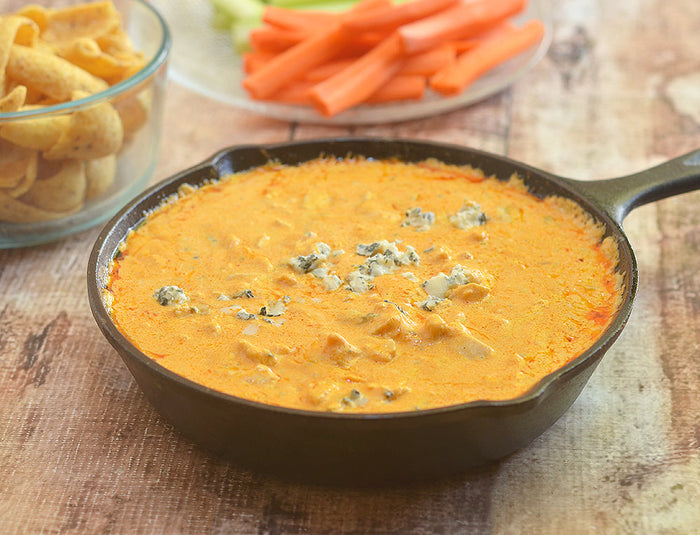 Buffalo blue cheese dip in a skillet with carrot sticks nearby