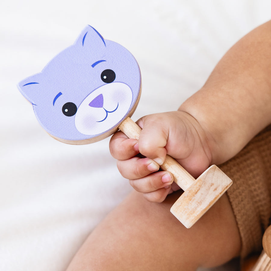 Baby holding a purple cat-shaped wooden rattle