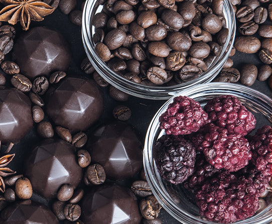 Coffee beans, chocolate and raspberries pictured as flavor inspiration for Chocolate Raspberry Truffle coffee