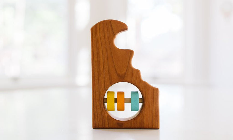 Delaware state-shaped cherry wood baby rattle with colored center disks
