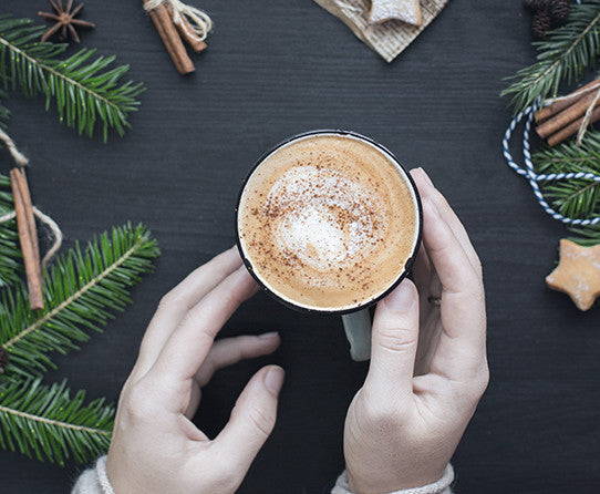 Serving suggestion: hands holding a cup of coffee with a gingerbread cookie