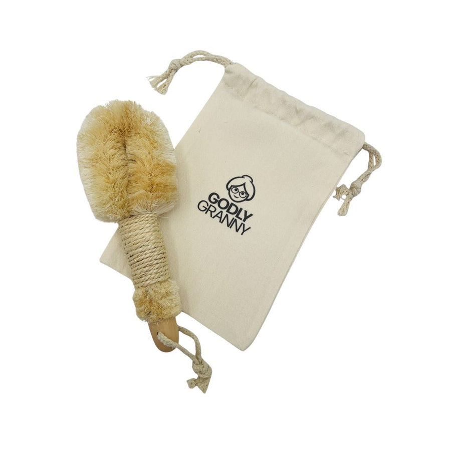 Wooden dry body brush beside a keepsake drawstring logo bag
