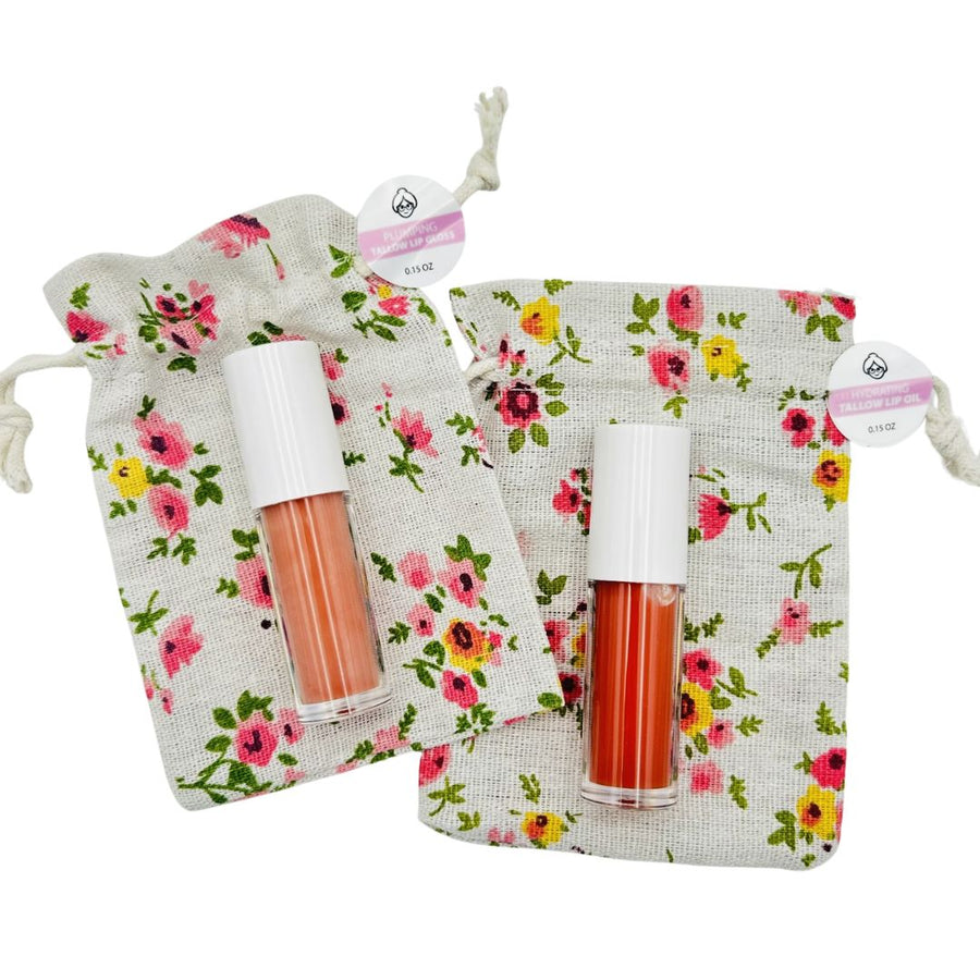 Two tallow lip gloss roller bottles beside floral drawstring bags