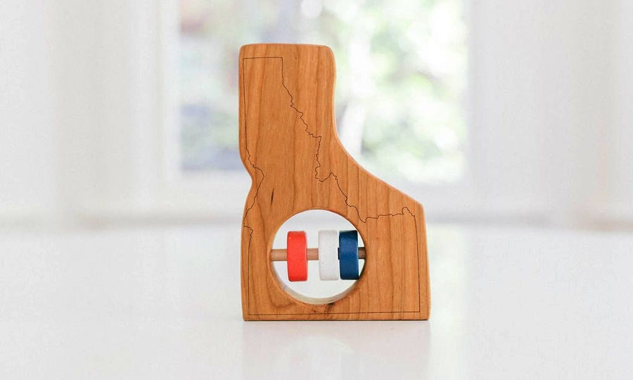 Idaho state-shaped cherry wood baby rattle with colored center disks