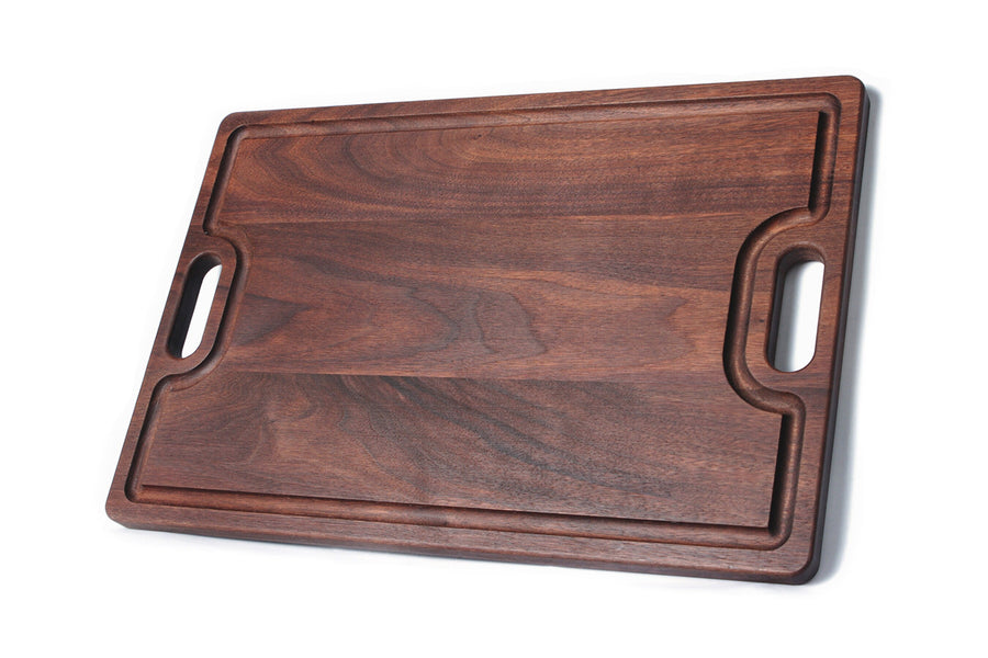 Walnut serving board showing a perimeter groove and two cutout handles