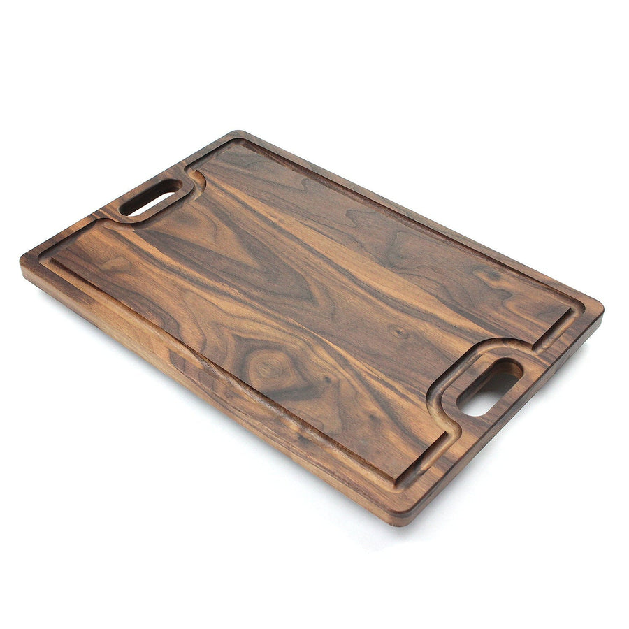 Angled view of a walnut cutting board with integrated handles