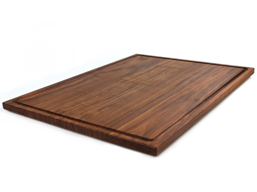 Large walnut cutting board with a juice groove, angled view