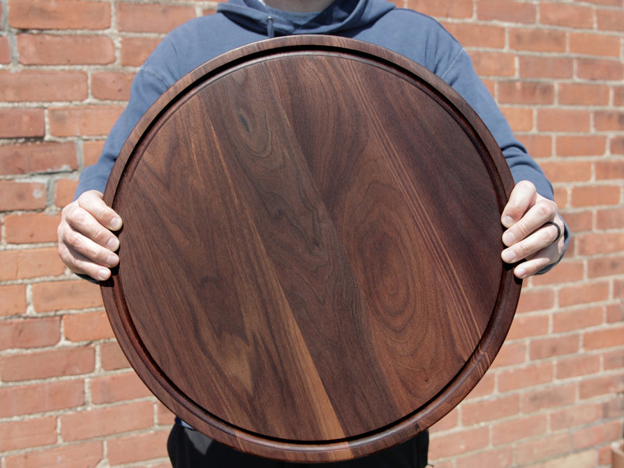 Person holding a round walnut cheese board
