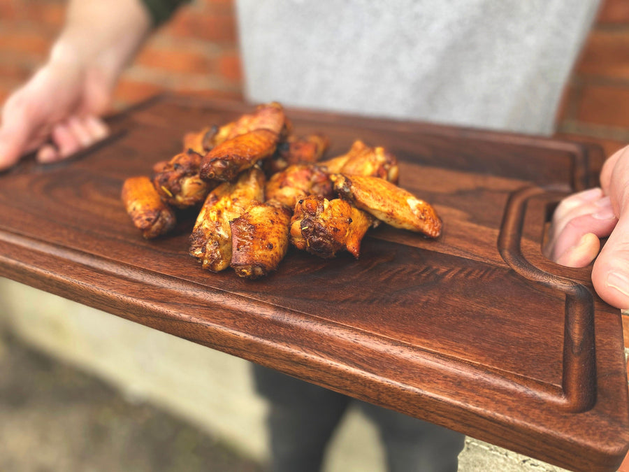 Walnut board with handles carrying prepared chicken wings