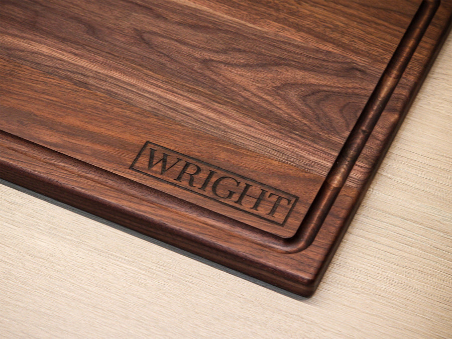 Close view of a surname engraved near a walnut board's corner