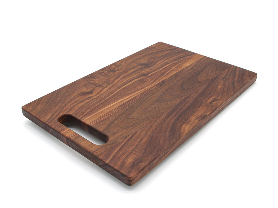 Walnut cutting board with a single cutout handle, angled view