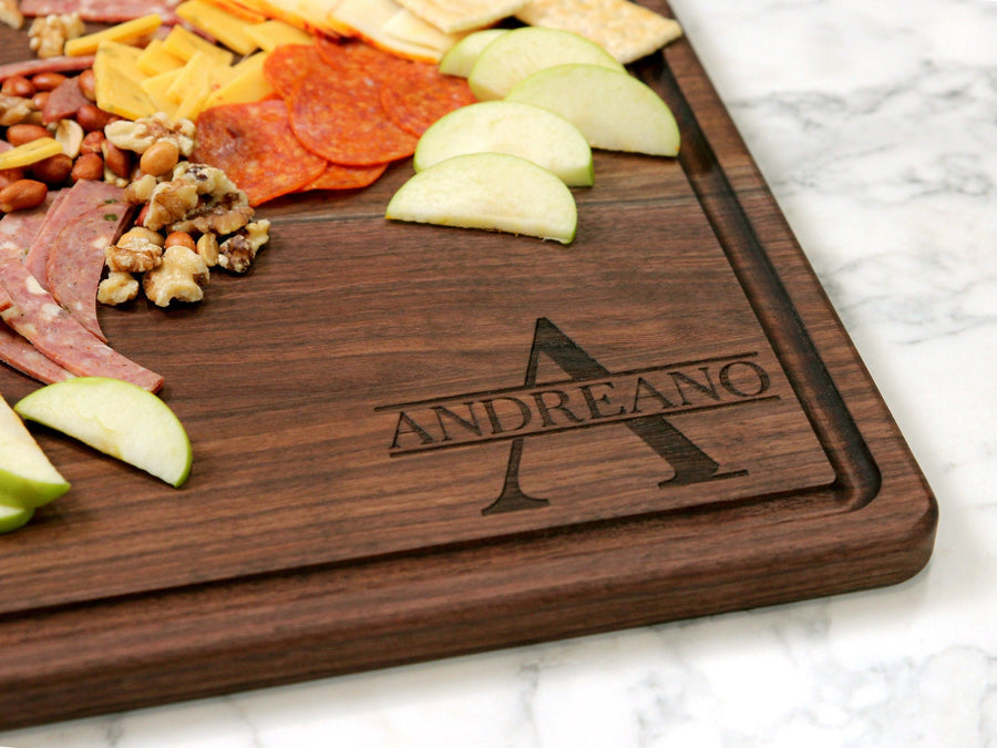 Walnut board with a monogram beside arranged cheeses and sliced fruit