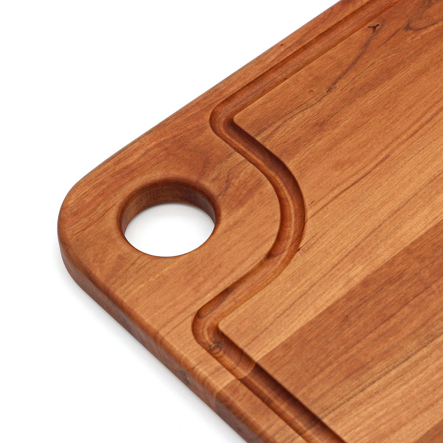 Close view of the circular thumb hole and juice groove in a cherry board