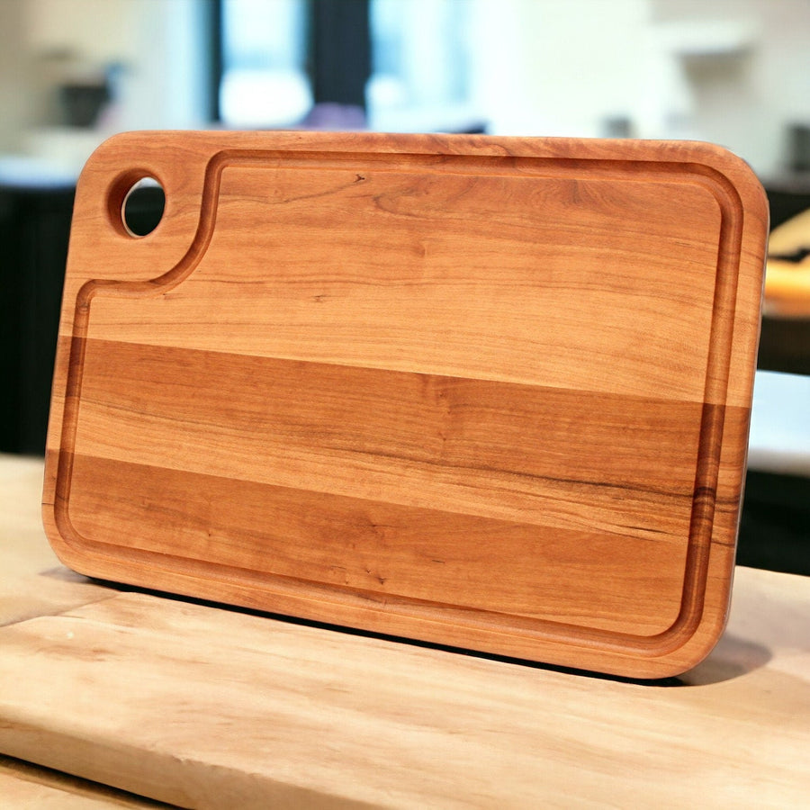 Cherry thumb-hole cutting board standing on a kitchen counter