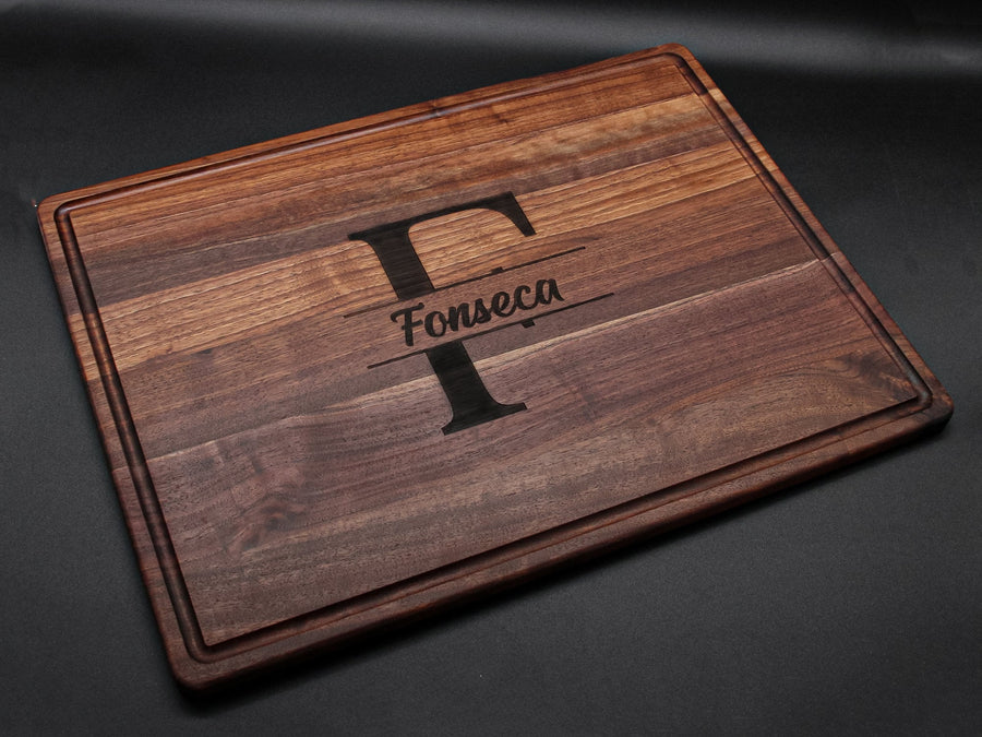 Engraved walnut board with a large letter monogram on a dark background