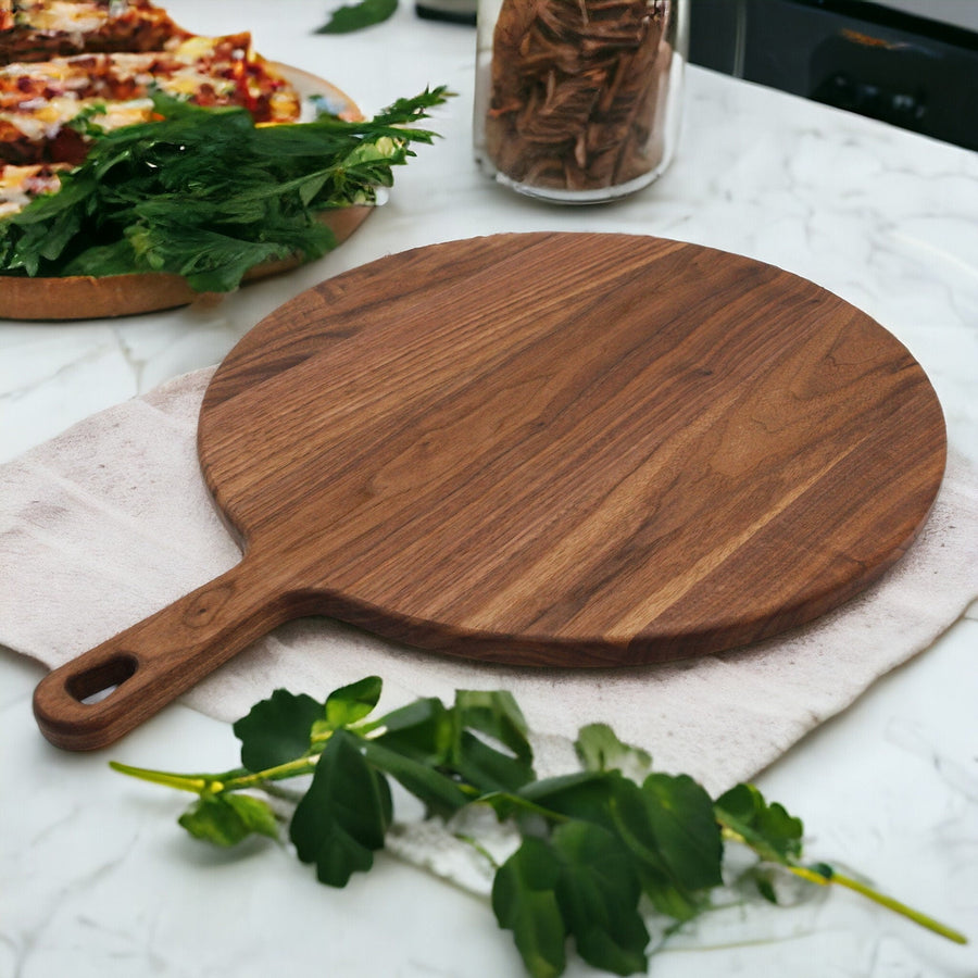 Round walnut serving paddle on a kitchen counter beside food and herbs