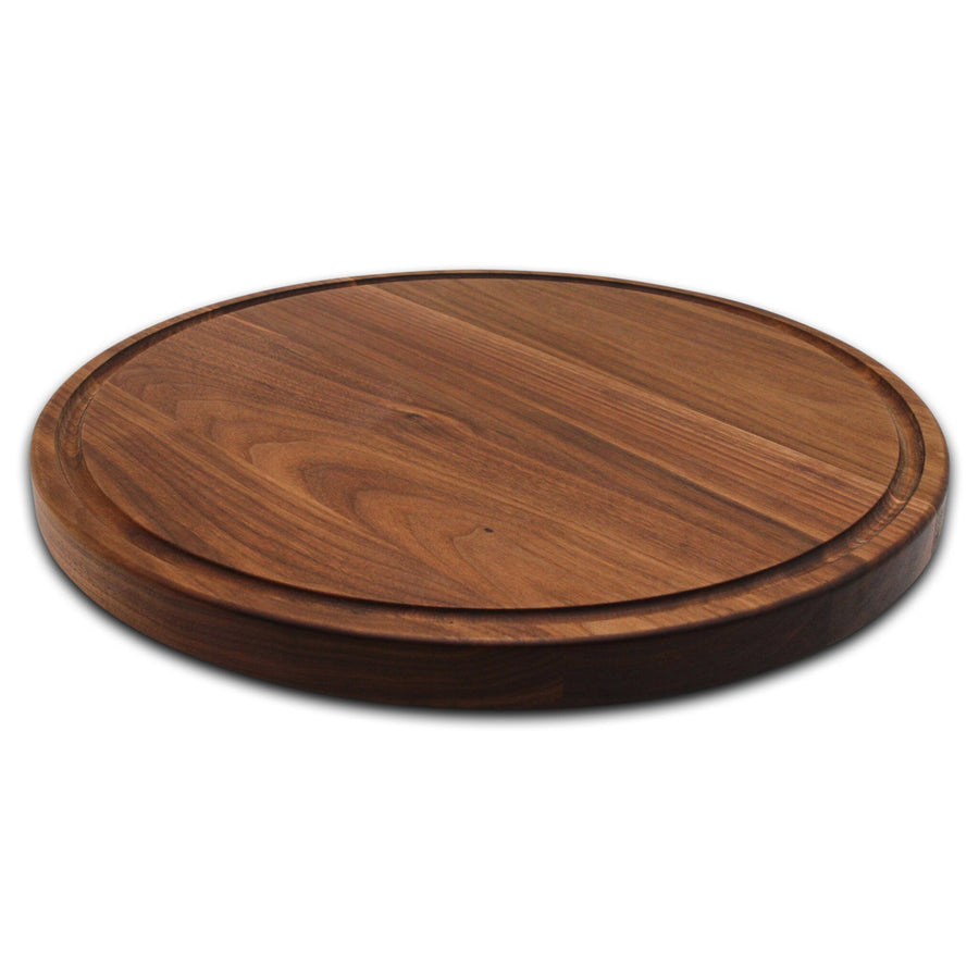 Round walnut cutting board with a juice groove, angled view