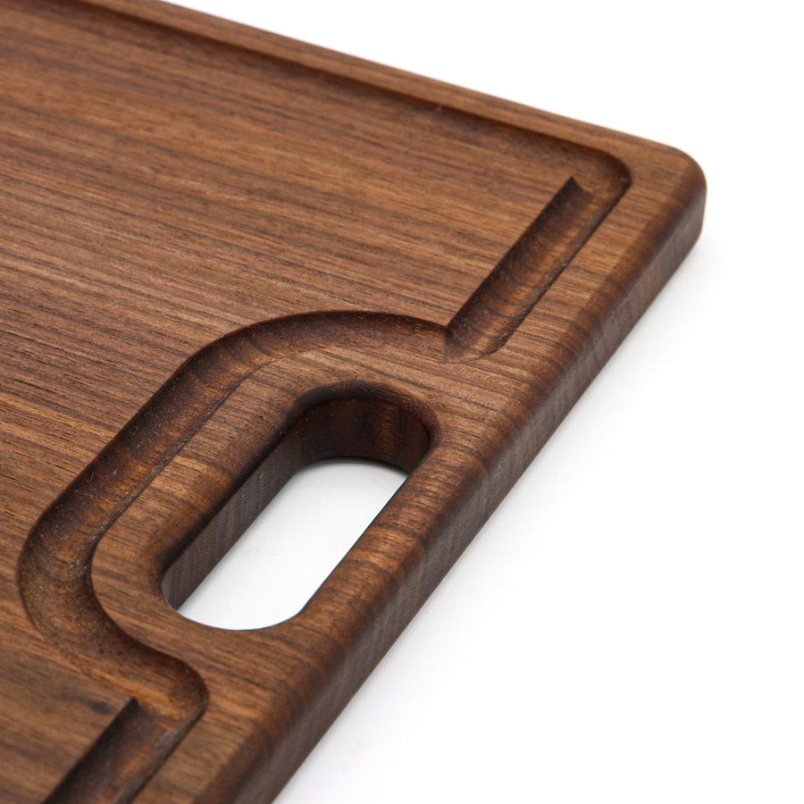 Close view of a walnut cutout handle and the surrounding juice groove